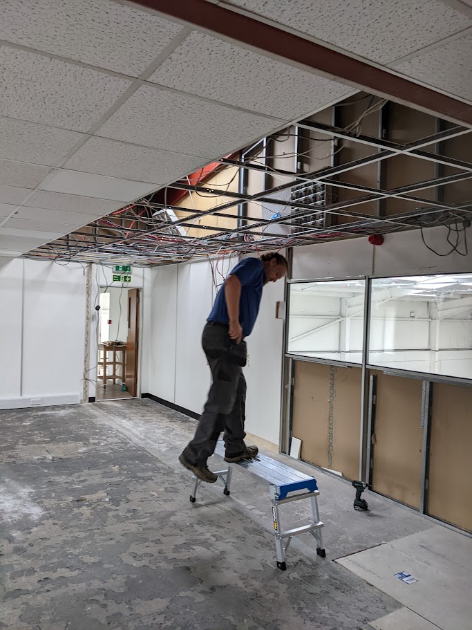 Suspended ceiling tiles and grid being removed during a commercial interior strip out